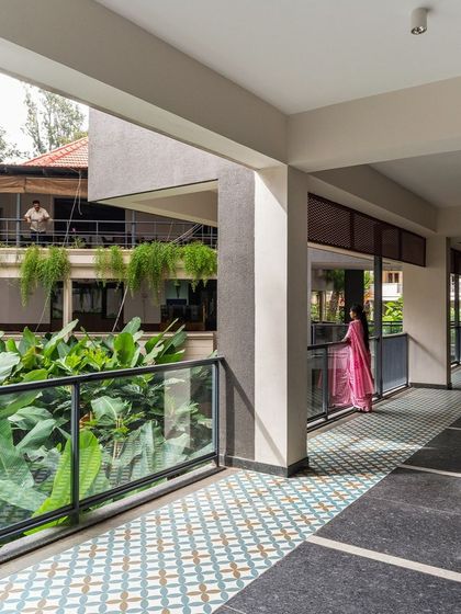 A wide corridor overlooking the club's courtyard, where patterned floor tiles and hanging plants create a pleasant, shaded walkway. These spaces, though not defined by a specific function, are vital to the project's atmosphere.