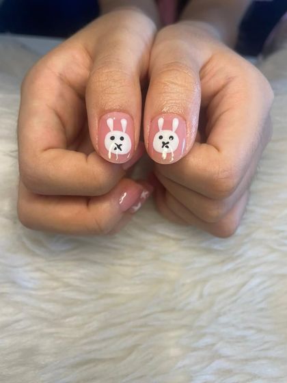 A close-up of some cute, hand-painted bunny art on short, natural nails.