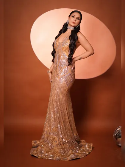 A side profile pose that accentuates the curves of the gown and the long, wavy hairstyle. This is a classic glamour shot, exuding confidence and style.