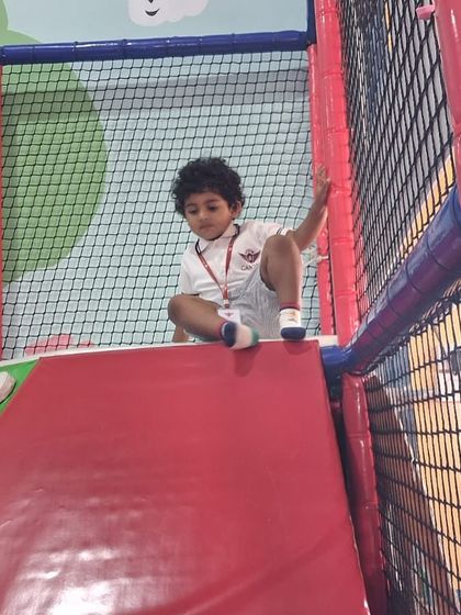 A child confidently navigating the top of a slide, ready for the fun ride down.