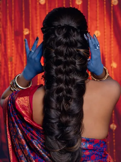 A creative look from an international hairstyle demo, showing a complex braid and unconventional blue hands for an artistic effect.