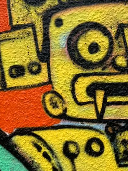 A close-up of the robot character's face. The thick black outlines and simple color palette give it a bold, cartoonish feel.