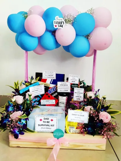 A thoughtful and fun gift for expecting fathers, this 'Dad-to-Be Survival Kit' is a perfect Father's Day surprise. It's filled with goodies and essentials, decorated with pink and blue balloons, and includes sweet notes 'from the baby'.