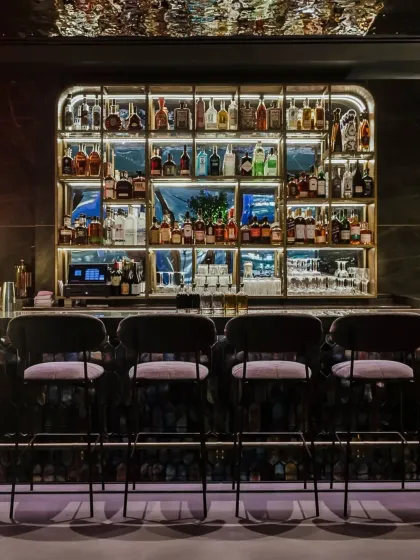 The sleek, well-lit bar at One40 Rooftop. We designed the back-lit shelving and marble countertop to create a sophisticated focal point for the restaurant.