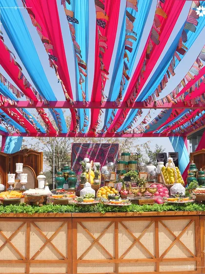 A vibrant daytime event in Bengaluru, with colourful drapes creating a festive canopy. Our buffet stations are designed to be both abundant and aesthetically pleasing, matching the event's energy.