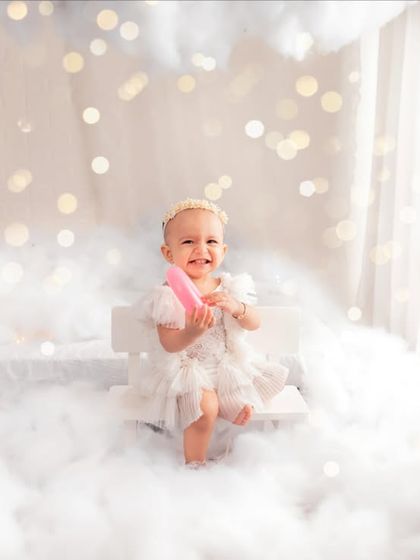 A little fairy coming your way, sitting on a bench in the clouds. The bokeh lights in the background add an extra layer of sparkle to this enchanting setup.