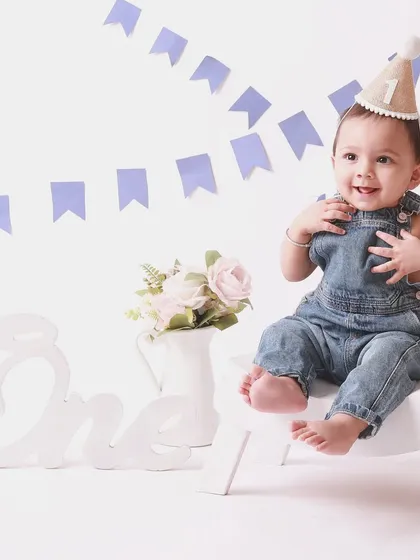 A classic first birthday setup with blue banners and a happy baby in denim overalls. Timeless, simple, and full of joy.