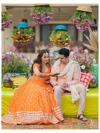 A sweet moment during the Mehendi ceremony, where the bride shows her henna-adorned hands to the groom.