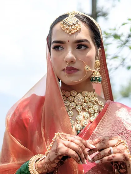 A stunning portrait of the bride in her traditional attire. The mountain scenery in the background adds a sense of grandeur to her natural beauty and elegance.