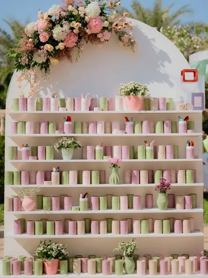 A beautiful and functional pastel favor wall, with favors rolled into scrolls and arranged by color, serving as both a gift station and a stunning piece of decor.
