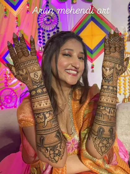 A happy client showing her full-arm bridal mehendi. The design includes personalized elements and traditional motifs, all done with my natural henna for a dark, beautiful stain.