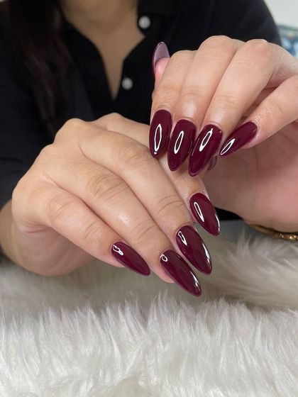 A stunning, deep maroon polish on long, almond-shaped nails for a simple yet dramatic look.
