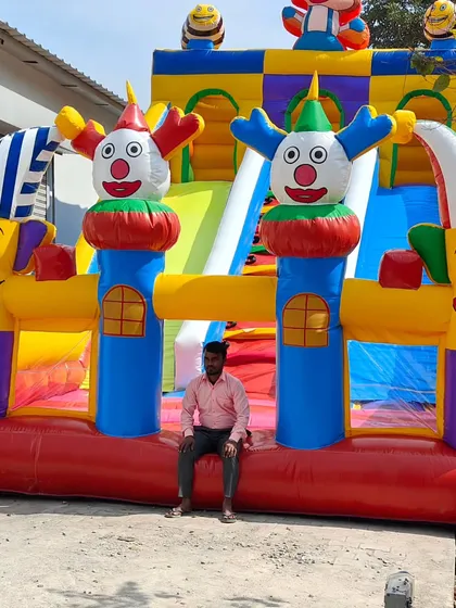 A person sitting in front of the clown-themed bouncy gives a sense of its large scale. It's built to handle commercial use at busy events.