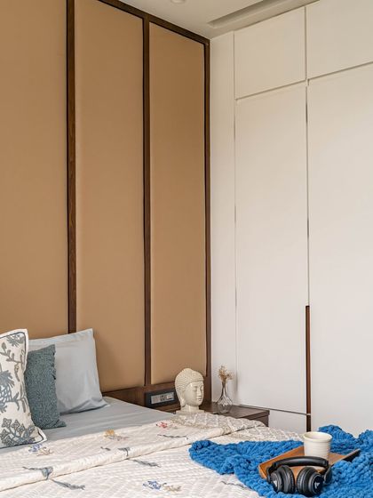 The kids' bedroom was designed with functionality at its heart. A full-wall leatherette headboard adds a cozy vibe, while sleek white cupboards provide ample storage to keep the room tidy and stylish.