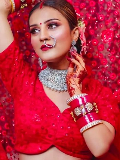 A bride in a vibrant red outfit, wearing a modern, wide diamond choker. This shows how you can pair contemporary jewellery with traditional colors for a unique look.
