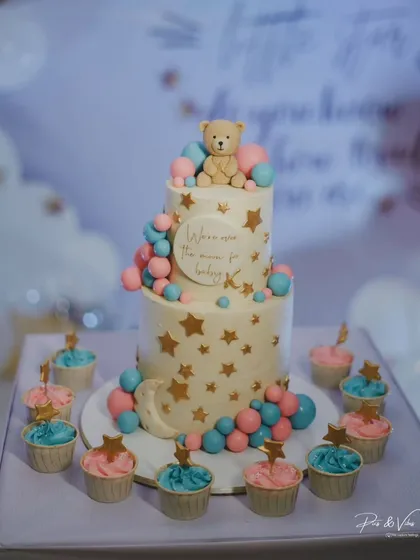 A full view of the dessert setup for Drashti Dhami's baby shower, including the two-tier cake and color-coordinated cupcakes.