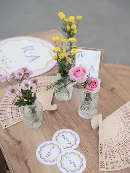 The table decor included personalized coasters, small floral arrangements, and wooden fans for guests.