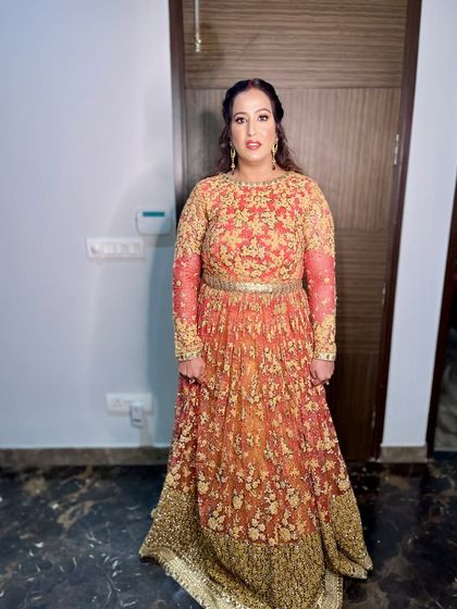 The full view of her stunning orange and gold anarkali.