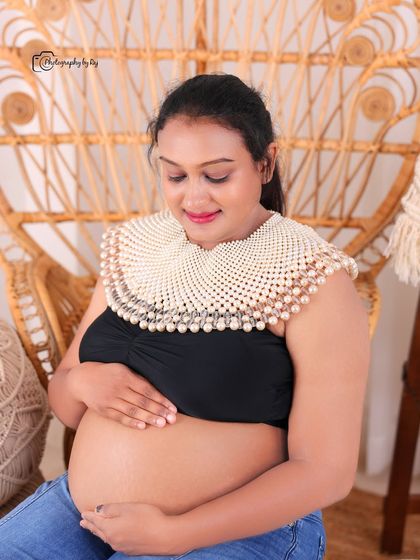 A beautiful bare-bump studio portrait. The mother-to-be is wearing a pearl collar accessory, adding a touch of elegance to this intimate shot.