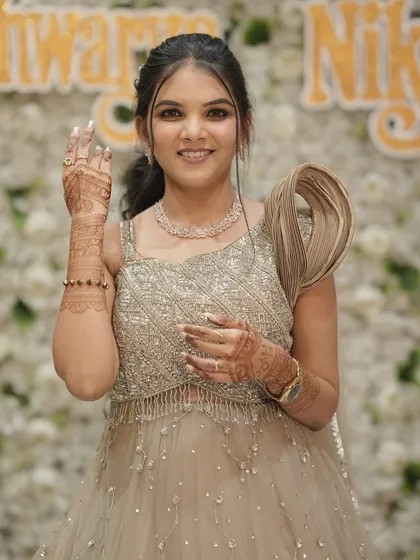 Waving to her guests, this bride shows off her modern engagement gown and elegant makeup. The focus is on radiant skin and a happy smile.