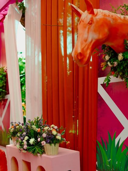 A detailed shot of the horse-themed decor, with a floral-wreathed horse sculpture against a vibrant pink and orange draped background.