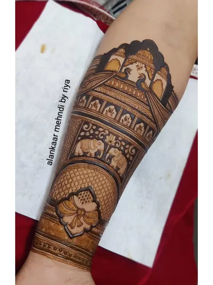 The nearly completed arm piece, showing multiple bands of intricate patterns including peacocks, elephants, and florals.