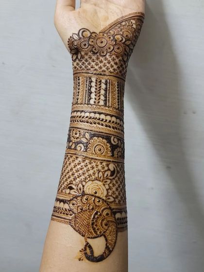 This design features a graceful elephant motif on the forearm, a symbol of good luck. It's surrounded by delicate floral patterns and geometric grids, creating a balanced and beautiful bridal arm piece.