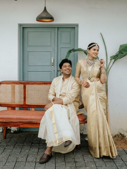 A classic portrait of Goutham and Aiswarya during their Hindu Brahmin wedding. Their coordinated outfits and joyful smiles are set against a backdrop of traditional decor.