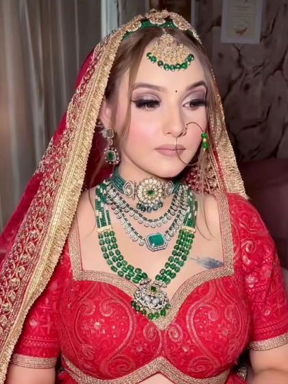 A bride in a red lehenga wearing a layered emerald bead and Kundan set. This Sabyasachi-inspired look is one of my most requested rental pieces.