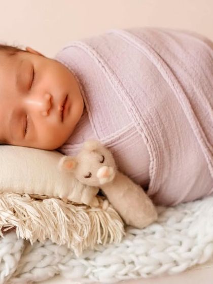 A perfect little bundle sleeping soundly. This photo showcases a full body wrap, which is ideal for keeping babies calm and posed beautifully in props like this tiny bed.