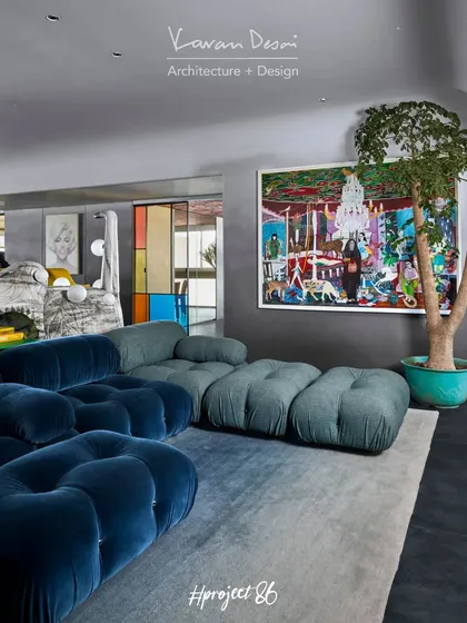 Another angle of the TV lounge, showing the large plant and colorful artwork that bring life to the space. The modular sofa allows for flexible seating arrangements, perfect for entertaining.