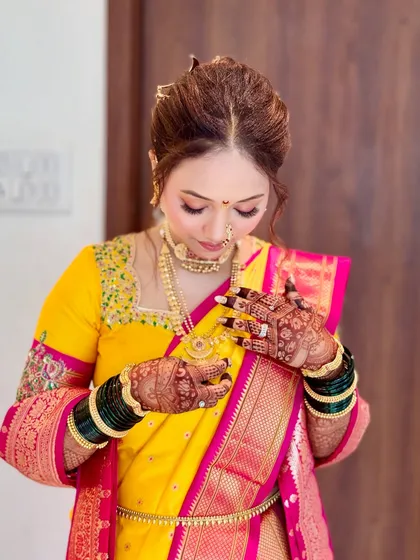 A bride admiring her jewelry. The makeup is balanced to complement the heavy gold jewelry without being overpowering.