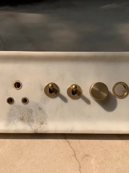 The final fabricated marble switch plate, with its subtle veining and cool, smooth surface. The brass elements provide a warm, tactile contrast.