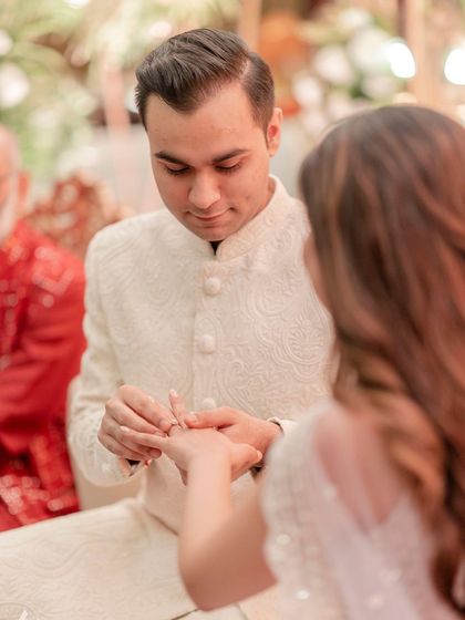 The groom gently places the engagement ring on his bride's finger, a classic and important shot.