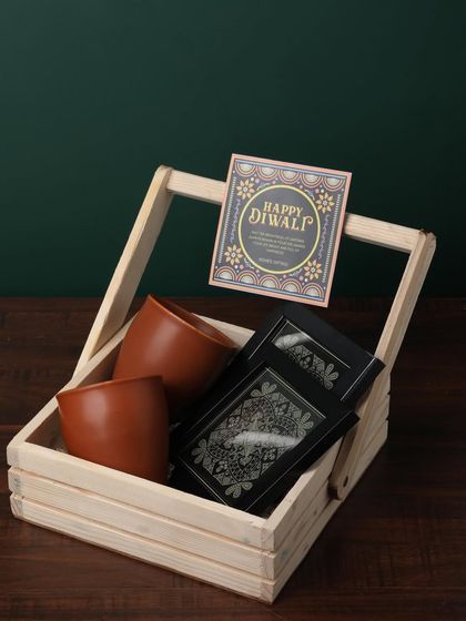 A simple and elegant arrangement in a wooden basket, this gift includes two terracotta kulhads and two boxes of premium chocolates, perfect for a client or colleague.