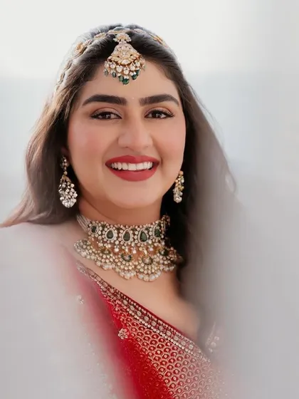 A stunning close-up of Vaishnavi. Her bright smile and radiant red bridal attire are a perfect match.