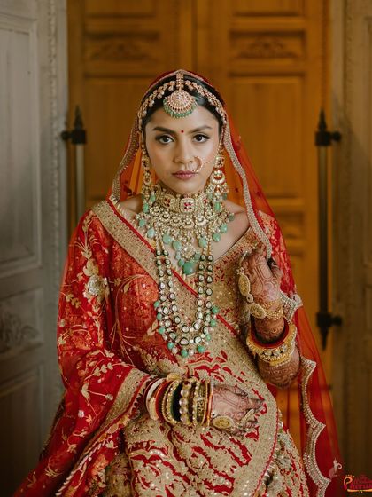 This look is a testament to tradition and elegance. The makeup is designed to be timeless, with a classic red bindi and a muted lip color that balances the richness of her bridal attire.