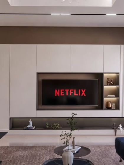 A close-up of the minimalistic TV unit at the Brigade Orchards villa, featuring clean lines, integrated shelving with backlighting, and a mix of closed and open storage.