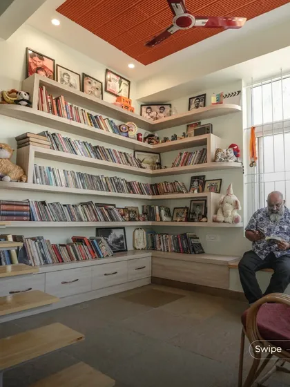 This cozy corner serves as a family library and reading nook. The custom-built shelves wrap around the corner, providing ample storage for books and memorabilia, while the built-in seating by the window is a perfect spot to read and relax.