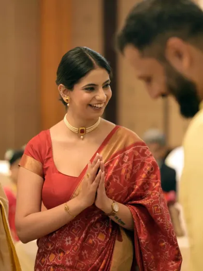 A beautiful candid shot of the bride-to-be with a welcoming smile and hands in a 'namaste' gesture.