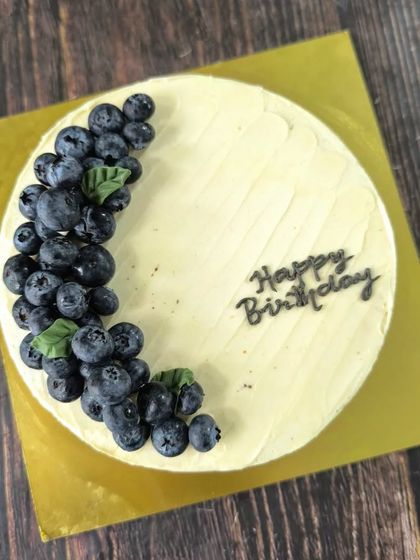 A berry special cake. This minimalist design features a simple cream cheese frosting and is beautifully decorated with a crescent of fresh blueberries.