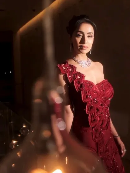 A timelessly elegant crimson one-shoulder gown, intricately embellished to perfection. The refined silhouette features a high slit, striking a balance between sophistication and modern allure.
