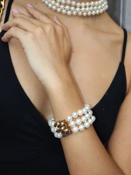 A close-up of our three-strand pearl bracelet with its intricate gold clasp, paired with a matching choker.