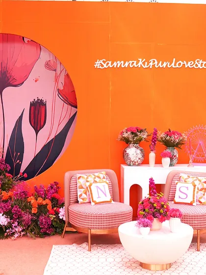 A personalized seating nook for the couple, complete with custom initialed pillows and a vibrant floral backdrop. Every detail is designed to tell their unique love story.