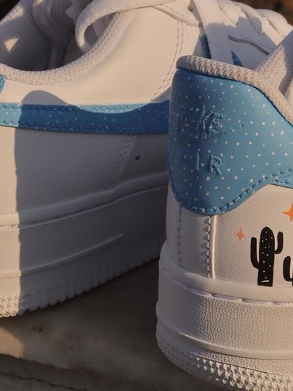 A close-up of the heel of the pastel-themed sneakers, showing the cute cactus illustrations and the polka-dot pattern on the heel tab.