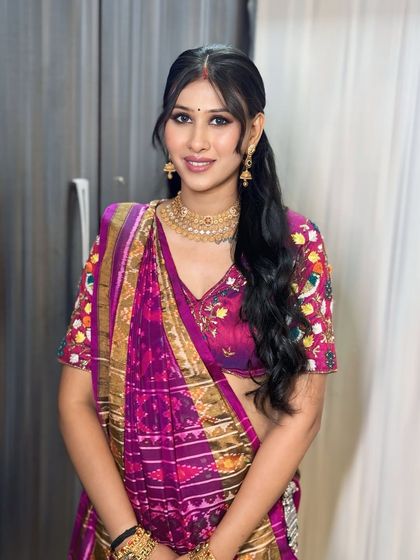 A modern take on a traditional look. This client is wearing a vibrant purple bandhani saree with a chic ponytail and glowing makeup.