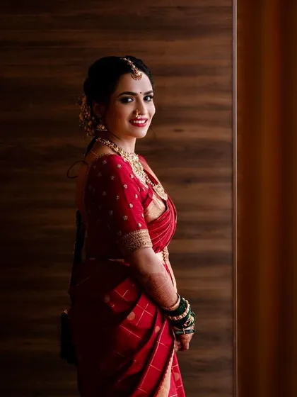 A bride in a classic red checkered saree. Her custom red blouse is simple and elegant, with subtle embroidery on the sleeves.