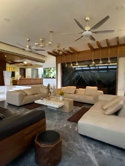An expansive open-plan living area in Mr. Satish's residence, showcasing a sophisticated palette of grey marble, warm wood accents, and layered lighting to create a luxurious yet inviting atmosphere.