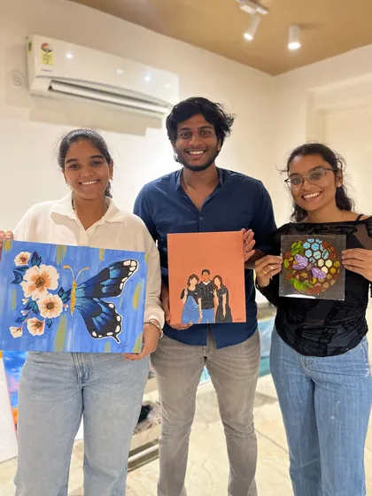 A group of three young adults with their impressive paintings, showcasing a variety of styles from portraiture to abstract.