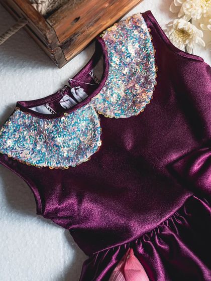 A close-up of the sparkling sequin Peter Pan collar on this rich wine-colored satin dress. It’s a fun and festive detail that is sure to make her shine.